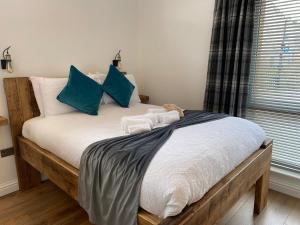 a bed with blue and white pillows and a window at Butterfly Cottage in Grantown on Spey