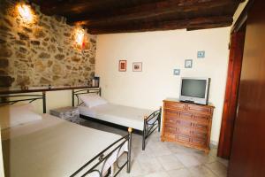 a room with two beds and a tv on a dresser at Corfu Ariandi Stone House in Giannádes