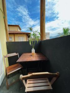 una mesa de madera y 2 sillas en el balcón en Hostel Caiçara Maresias en São Sebastião