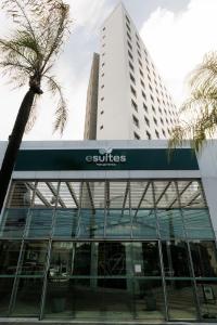 a building with a suture sign in front of a palm tree at eSuites Belo Horizonte Minascasa in Belo Horizonte