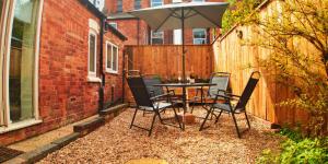 um pátio com uma mesa, cadeiras e um guarda-sol em Large Room in Modern House near Nottingham em Nottingham