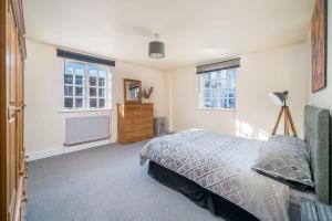 a bedroom with a bed and a dresser and two windows at TruStay Apartments London Bridge in London
