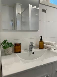 a bathroom sink with a mirror and a soap dispenser on it at Cozy apartment with a view in Tromsø +8 photos