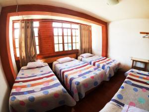 three beds in a room with a window at HOSPEDAJE SCHASCA in Oxapampa