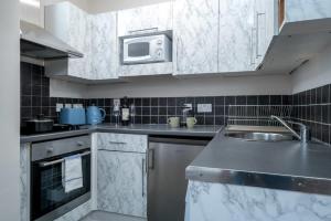 a kitchen with a sink and a microwave at City of London Lovely Two Bedroom Apartment in London
