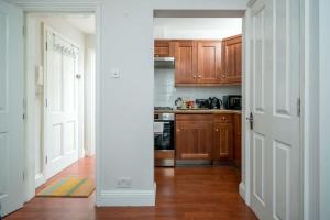 a kitchen with wooden cabinets and an open door at TruStay Apartments London Brick Lane in London