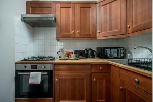a kitchen with wooden cabinets and a stove top oven at TruStay Apartments London Brick Lane in London