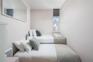 two beds in a room with white walls at City of London Lovely Two Bedroom Apartment in London