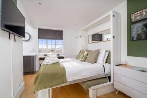 a white bedroom with a bed and a kitchen at Chelsea, London - Lovely Studio Apartment in London
