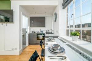 a kitchen with white counters and a large window at Chelsea, London - Lovely Studio Apartment in London