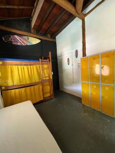 an empty room with yellow lockers and a door at Hostel Caiçara Maresias in São Sebastião