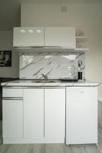a kitchen with white cabinets and a marble counter top at Fox Apartment in Gevgelija