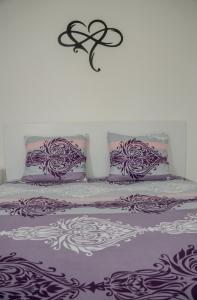 a bed with purple and white sheets and pillows at Fox Apartment in Gevgelija