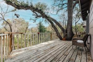 a wooden deck with a chair and a tree at Two Tree-House Oasis on UT Campus in Austin