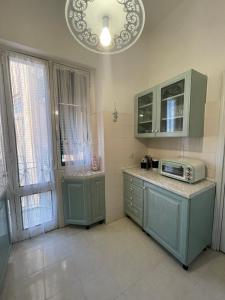 a kitchen with mint green cabinets and a microwave at A un passo dal mare! in Piombino