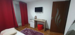 ein Schlafzimmer mit einem kleinen Schreibtisch und einem TV an der Wand in der Unterkunft Casa Yna in Horezu