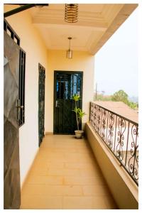 einen Balkon mit einer schwarzen Tür und einer Topfpflanze in der Unterkunft Résidences K and D in Bafoussam