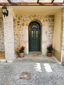 a green door in a stone building with flowers at Corfu Ariandi Stone House in Giannádes