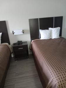 a hotel room with two beds and a night stand at RELAX INN in Rockingham