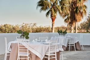 a table with white chairs and a white fence and palm trees at Il Trappetello in Monopoli