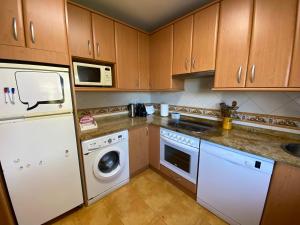 cocina con armarios de madera, lavadora y secadora en Casa Roji, en Loredo