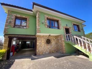 una casa verde con una escalera delante de ella en Casa Roji, en Loredo