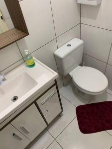 a white bathroom with a toilet and a sink at Casa com Piscina em Região Nobre de Cascavel in Cascavel