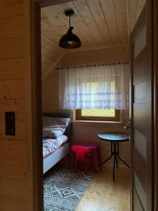 um quarto com uma cama, uma mesa e uma janela em Gładyszówka - Chatka w Gorcach em Ponice