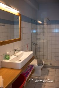 W łazience znajduje się umywalka, toaleta i lustro. w obiekcie Uranus Blue Residence Agios Ioannis Papa Nero w mieście Agios Ioannis Pelio