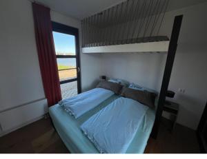 恩克赫伊曾的住宿－Strand Chalet am IJsselmeer Haus 214，一间卧室配有双层床和窗户。