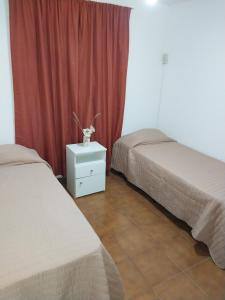 2 camas en una habitación con cortina roja en Hospedaje Isabelina en Las Heras