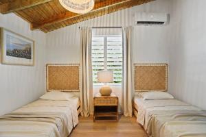 two beds in a room with a window at Villa Costera Joyuda in Cabo Rojo