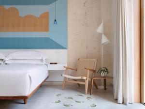 ein Schlafzimmer mit einem Bett und einem Stuhl in der Unterkunft Kimpton Las Mercedes, an IHG Hotel in Santo Domingo