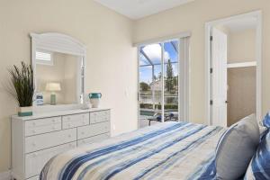 een slaapkamer met een bed, een dressoir en een spiegel bij Cape Serenity- Luxury Waterfront Villa with Kayaks in Cape Coral