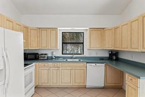 a kitchen with wooden cabinets and a sink and a window at Captiva Beach Bungalow on Turner Beach in Captiva