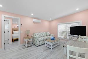 a living room with a couch and a flat screen tv at Charming Suite with Balcony and Bikes at Historic Sandpiper Inn in Sanibel