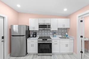 a kitchen with white cabinets and a stainless steel refrigerator at Charming Suite with Balcony and Bikes at Historic Sandpiper Inn in Sanibel