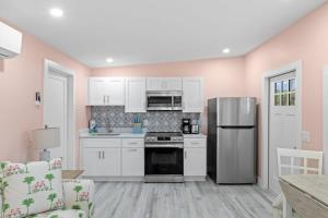 a kitchen with white cabinets and a stainless steel refrigerator at Charming Suite with Balcony and Bikes in Historic Sandpiper Inn in Sanibel