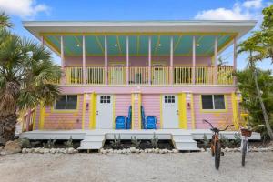 a pink and yellow house with a bike parked in front at Charming Suite with Balcony and Bikes in Historic Sandpiper Inn in Sanibel