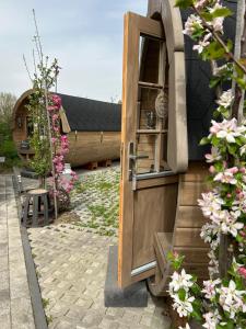 uma porta aberta para uma casa com flores em Schlaffässer auf dem Krügele Hof em Murr