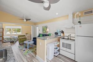 a kitchen and living room with a white refrigerator at Renovated Cottage at the Historic Palms Inn of Sanibel- Includes Pool and Bikes in Sanibel