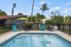 a swimming pool with blue chairs and umbrellas at Renovated Cottage at the Historic Palms Inn of Sanibel- Includes Pool and Bikes in Sanibel