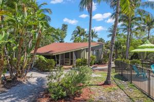 a house with a fence and palm trees at Renovated Cottage at the Historic Palms Inn of Sanibel- Includes Pool and Bikes in Sanibel