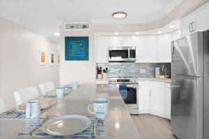 a white kitchen with a table and a refrigerator at Family-Friendly Bayside Villa at South Seas Resort in Captiva