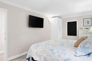 a white bedroom with a bed and a flat screen tv at Family-Friendly Bayside Villa at South Seas Resort in Captiva