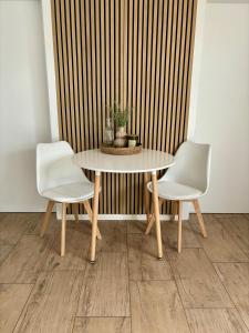 a table with two white chairs and a table with a plant at Home & Apart - Apartment im Herzen von Kreyenbrück - Apartment 1 in Oldenburg