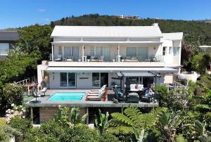 a large white house with a swimming pool at Lasalle holiday home (Sun, Beach, Views, Fun for everyone!) in Plettenberg Bay