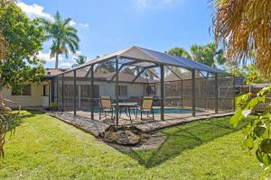 a glass house with a table and chairs in a yard at Cute Coastal Home with Pool in Fort Myers