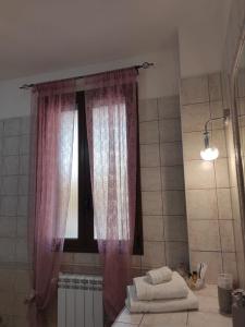 baño con ventana y cortinas rosas en Le Residenze di Niso en Siracusa