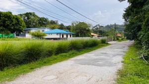 un chemin de terre avec une maison et un peu d'herbe dans l'établissement Blue Home2 T3 meublé à Matoury pour 1 à 6 voyageurs., à Matoury